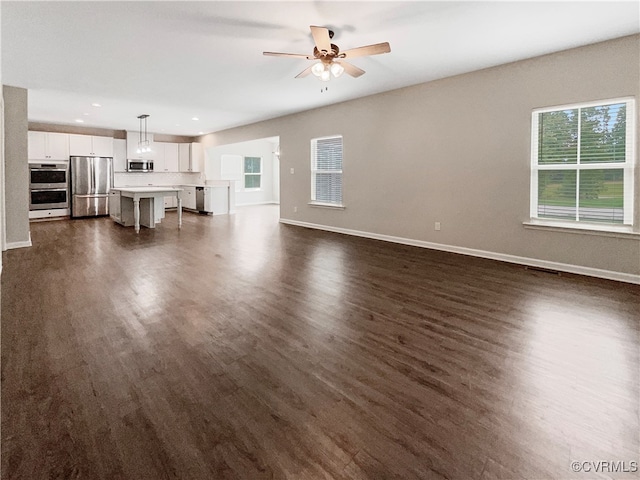 unfurnished living room with ceiling fan and dark wood-type flooring