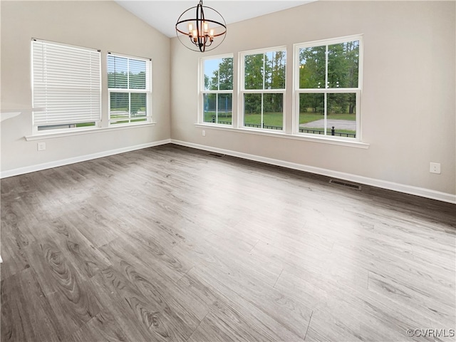 unfurnished dining area featuring an inviting chandelier, hardwood / wood-style flooring, and vaulted ceiling