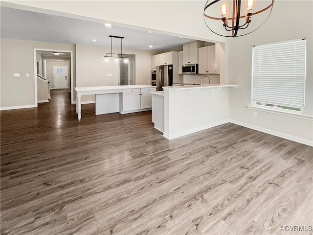 kitchen with wood-type flooring, pendant lighting, appliances with stainless steel finishes, and a breakfast bar