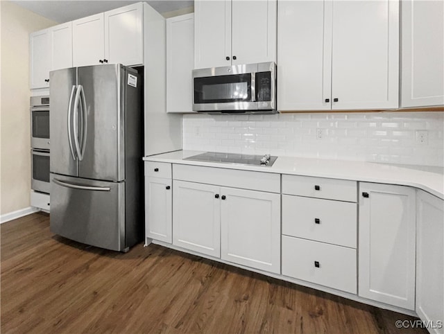 kitchen featuring stainless steel appliances, white cabinets, dark wood-type flooring, and tasteful backsplash