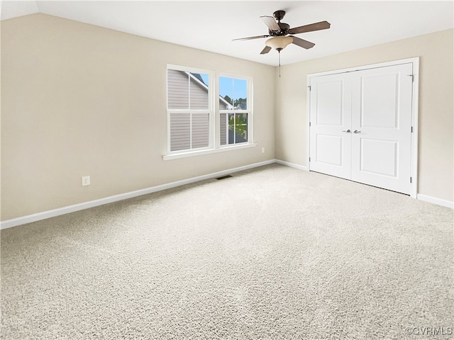 unfurnished bedroom with ceiling fan, carpet floors, lofted ceiling, and a closet