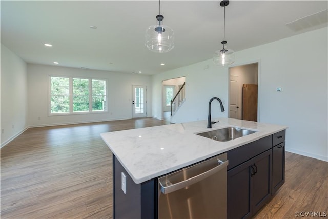 kitchen with dishwasher, pendant lighting, a center island with sink, sink, and light hardwood / wood-style flooring