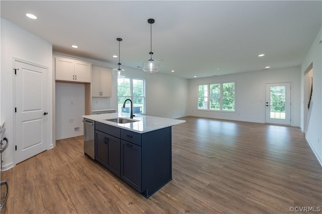 kitchen featuring decorative light fixtures, dishwasher, sink, a kitchen island with sink, and white cabinets