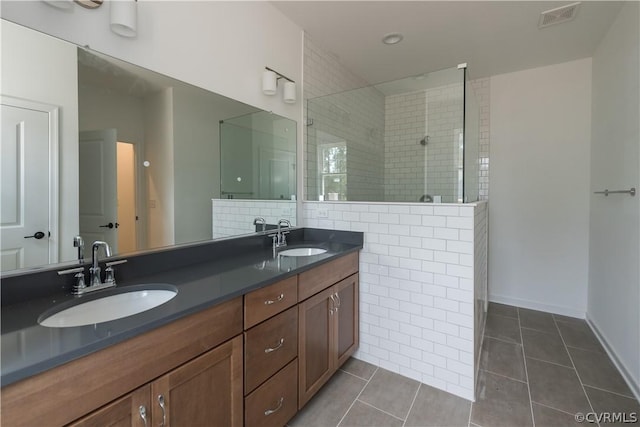 bathroom with decorative backsplash, tiled shower, vanity, and tile patterned flooring