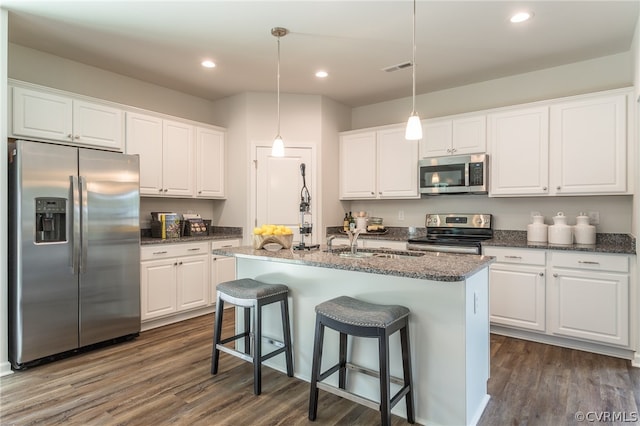 kitchen featuring white cabinetry, pendant lighting, an island with sink, dark hardwood / wood-style floors, and appliances with stainless steel finishes