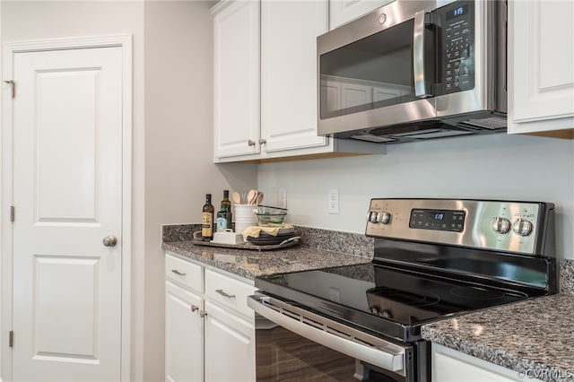 kitchen featuring dark stone counters, stainless steel appliances, and white cabinets