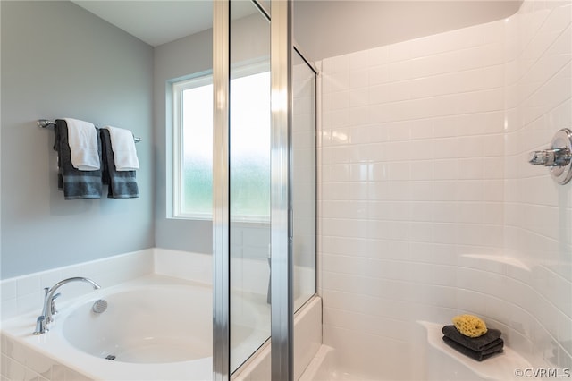 bathroom featuring tiled tub and a wealth of natural light