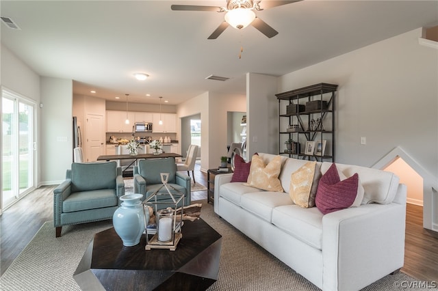 living room featuring wood-type flooring, ceiling fan, and plenty of natural light