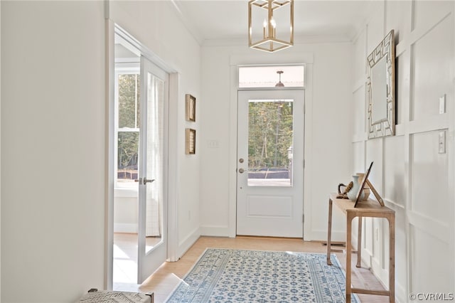 doorway to outside featuring a healthy amount of sunlight, ornamental molding, and light wood-type flooring