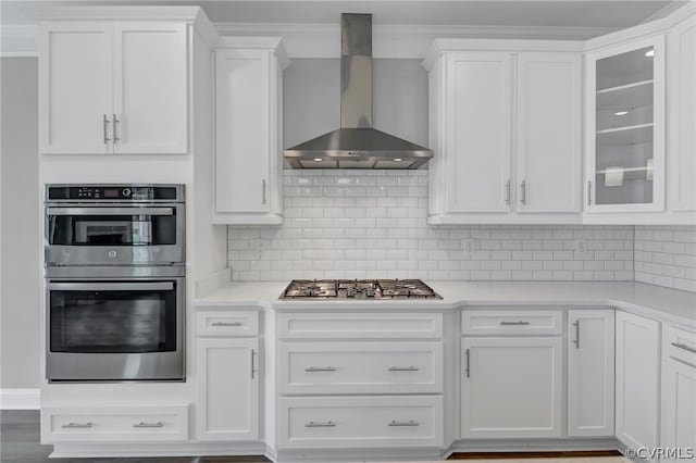 kitchen with wall chimney exhaust hood, appliances with stainless steel finishes, and white cabinetry