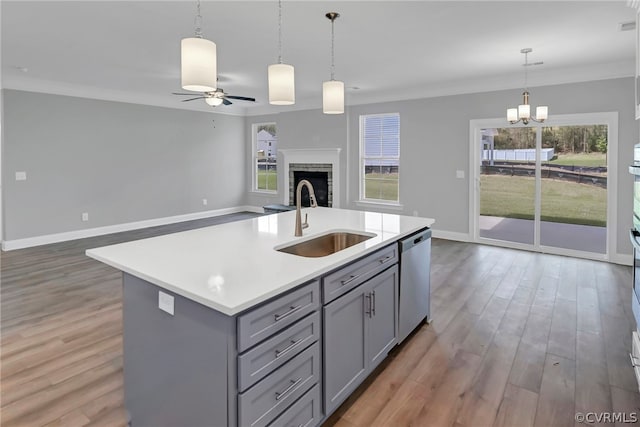 kitchen with sink, an island with sink, dishwasher, and hardwood / wood-style flooring