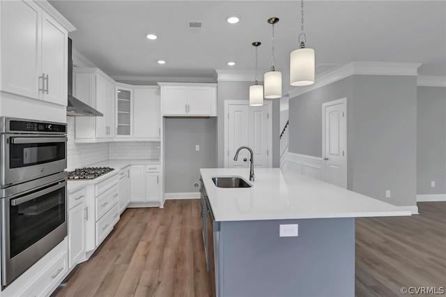 kitchen featuring hanging light fixtures, sink, an island with sink, and white cabinets