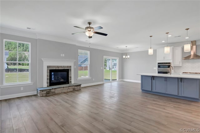 unfurnished living room with a stone fireplace, light wood-type flooring, and a wealth of natural light