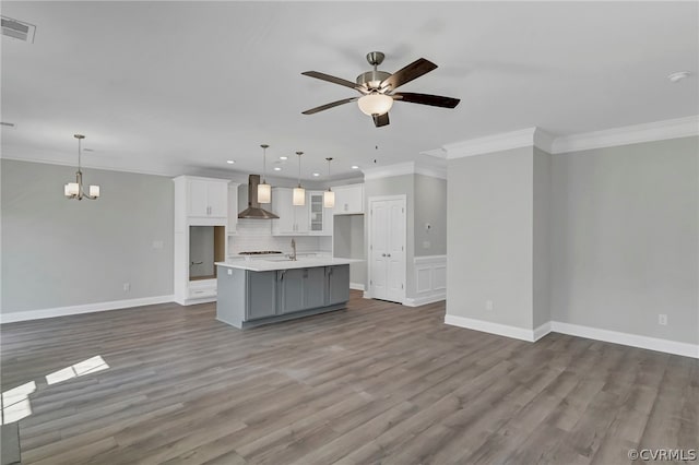 unfurnished living room featuring ornamental molding, sink, hardwood / wood-style flooring, and ceiling fan with notable chandelier