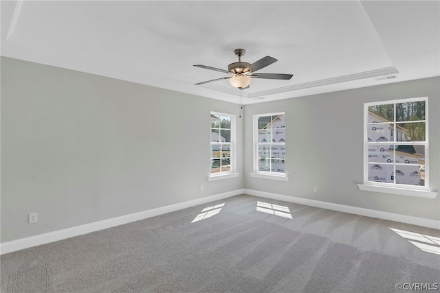 carpeted empty room with ceiling fan, a raised ceiling, and a wealth of natural light