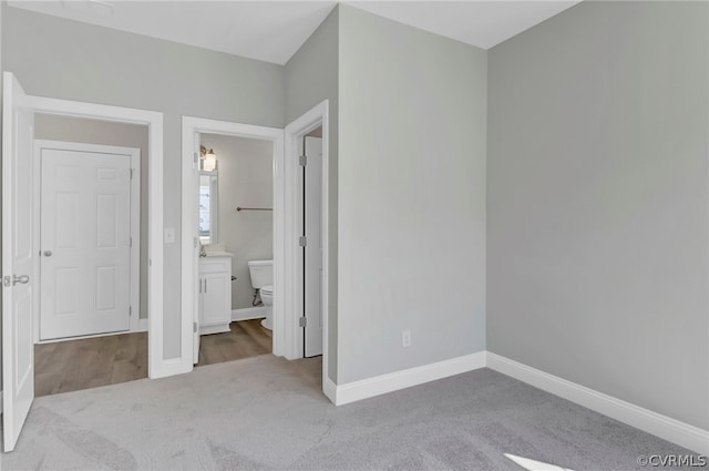 unfurnished bedroom featuring light carpet and ensuite bath