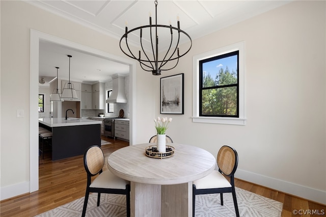 dining space featuring wood-type flooring, sink, and a chandelier