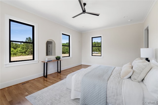 bedroom featuring crown molding, ceiling fan, multiple windows, and hardwood / wood-style floors