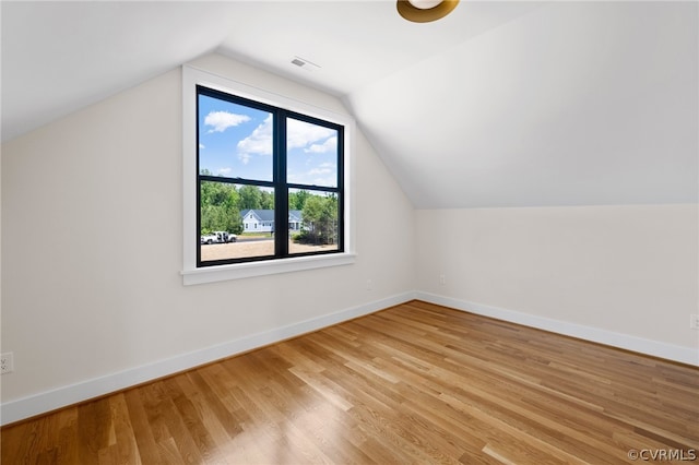 additional living space with light hardwood / wood-style floors and vaulted ceiling