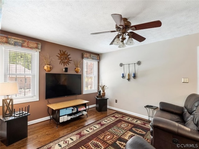 living room featuring ceiling fan, hardwood / wood-style flooring, and a textured ceiling