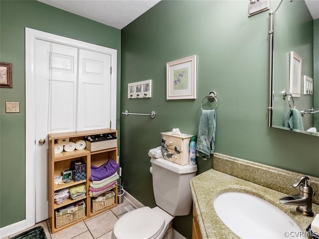 bathroom with tile flooring, oversized vanity, toilet, and a textured ceiling