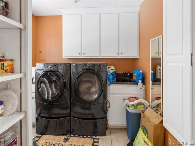 laundry room with cabinets, sink, light tile flooring, and washer and clothes dryer