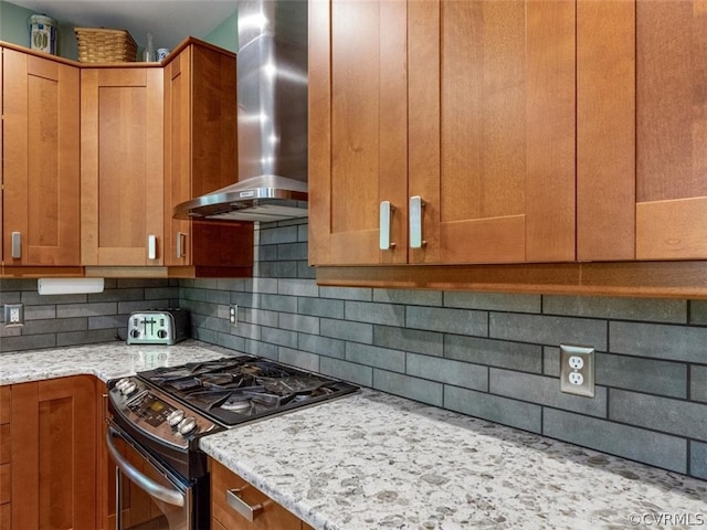 kitchen with light stone counters, wall chimney exhaust hood, range with gas cooktop, and tasteful backsplash