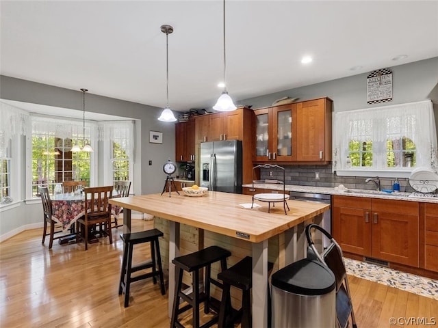 kitchen featuring a healthy amount of sunlight, hanging light fixtures, light hardwood / wood-style flooring, and stainless steel appliances