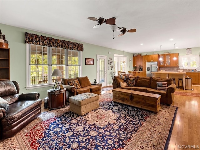 living room with a wealth of natural light, wood-type flooring, sink, and ceiling fan