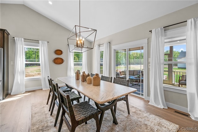 dining area featuring a notable chandelier, vaulted ceiling, plenty of natural light, and light hardwood / wood-style floors