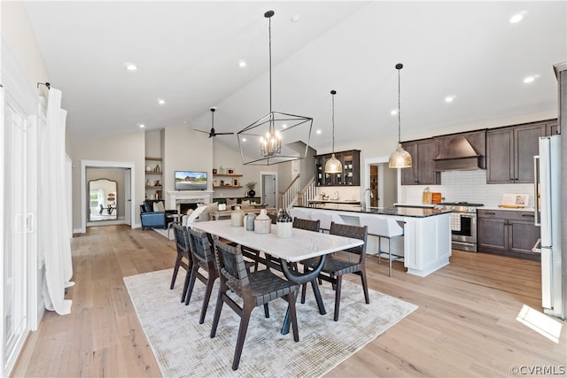 dining area featuring high vaulted ceiling, an inviting chandelier, and light wood-type flooring