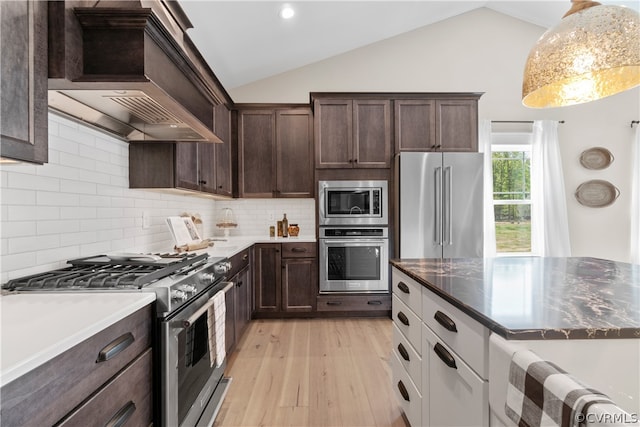 kitchen featuring light hardwood / wood-style flooring, tasteful backsplash, vaulted ceiling, custom range hood, and premium appliances