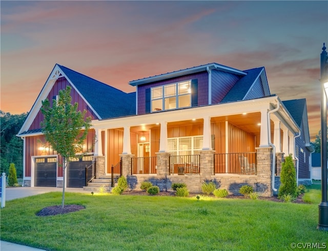 view of front of property featuring a garage, a yard, and covered porch