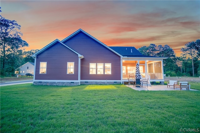 back house at dusk featuring a yard