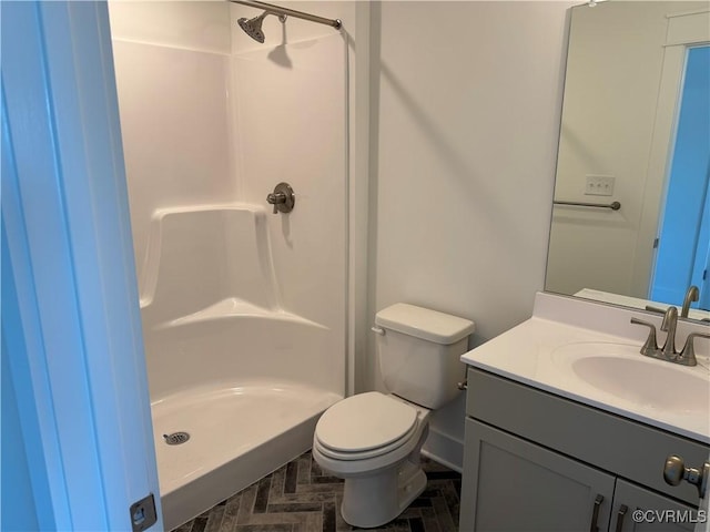 bathroom with vanity, a shower stall, and toilet