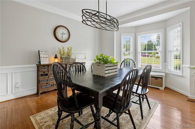 dining room with crown molding, a healthy amount of sunlight, and light wood-type flooring