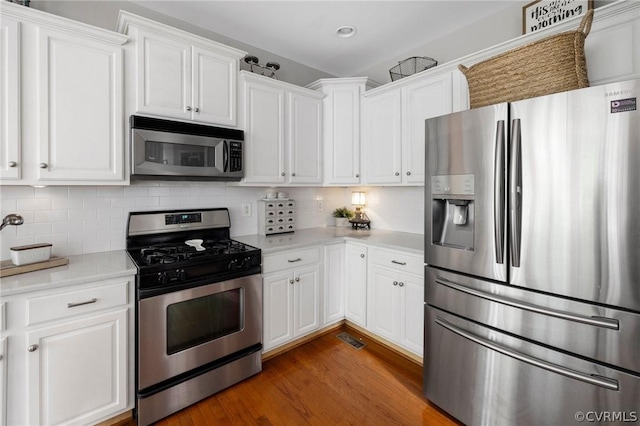 kitchen featuring white cabinetry, dark wood-type flooring, stainless steel appliances, and tasteful backsplash