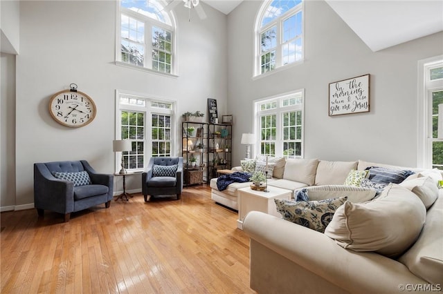 living room with a towering ceiling, light hardwood / wood-style flooring, and ceiling fan