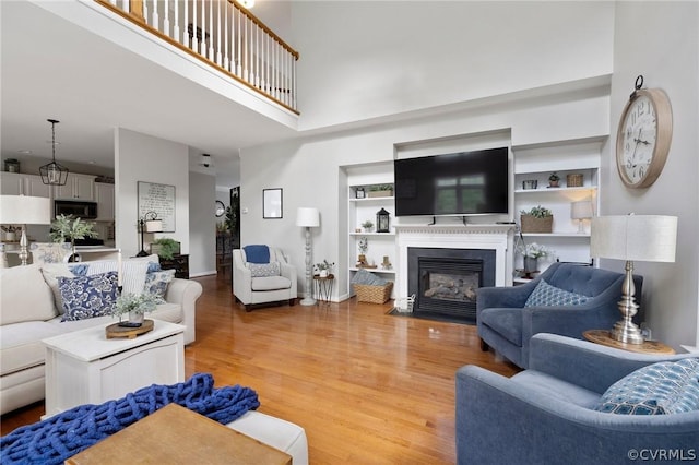 living room with a towering ceiling, hardwood / wood-style floors, and built in shelves