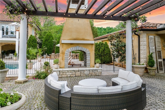 patio terrace at dusk featuring a pergola and an outdoor living space with a fireplace