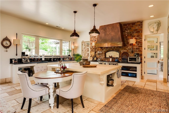 interior space featuring pendant lighting, a center island, light tile flooring, and custom exhaust hood