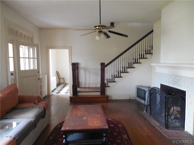 living room with ceiling fan, a tile fireplace, and hardwood / wood-style flooring