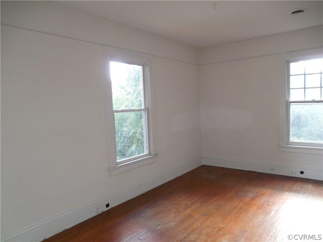 spare room featuring dark hardwood / wood-style flooring and plenty of natural light