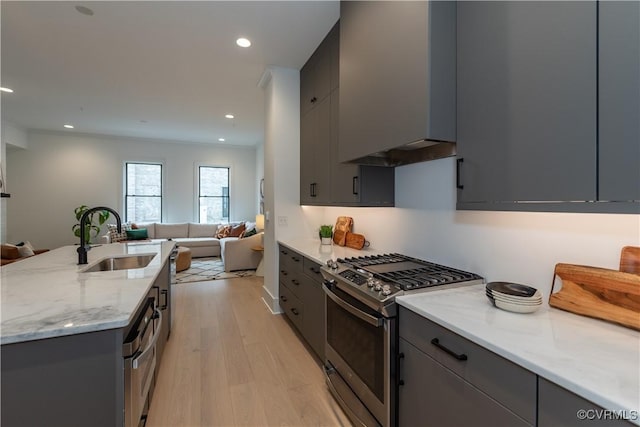 kitchen featuring a sink, stainless steel gas stove, open floor plan, and gray cabinets