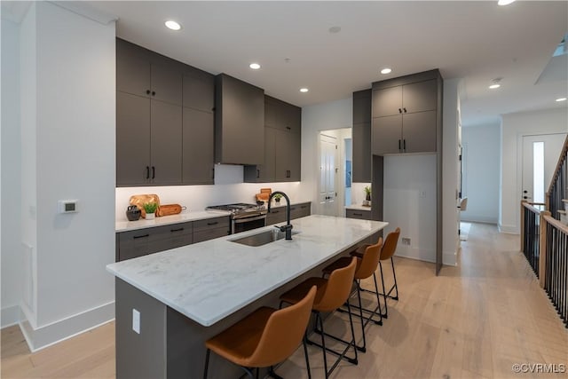 kitchen featuring a sink, a breakfast bar, recessed lighting, and light wood finished floors