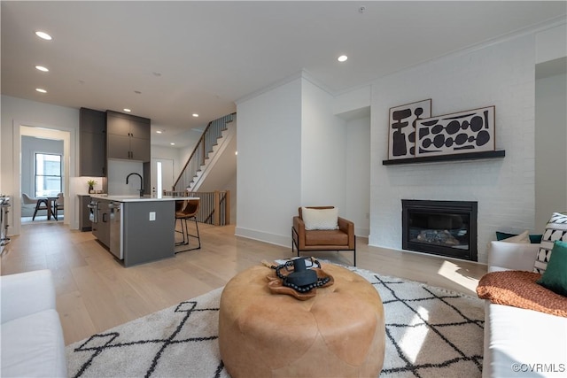 living room featuring stairway, baseboards, recessed lighting, light wood-type flooring, and a large fireplace