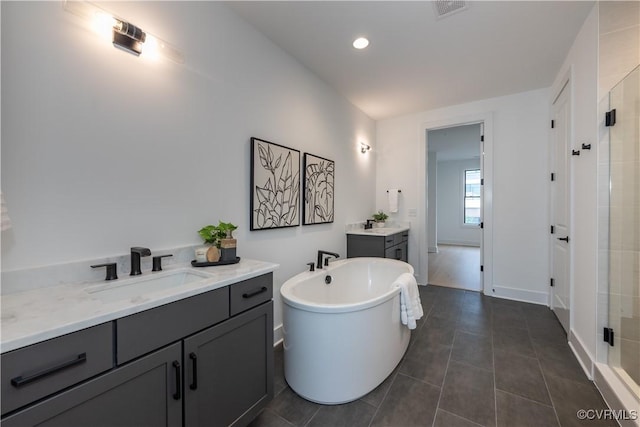 full bathroom with visible vents, two vanities, a freestanding bath, a sink, and a shower stall