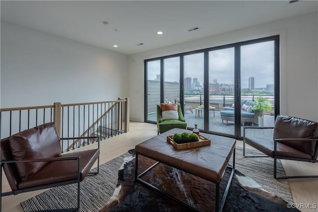 sitting room featuring a wealth of natural light, light wood-type flooring, a view of city, and an upstairs landing