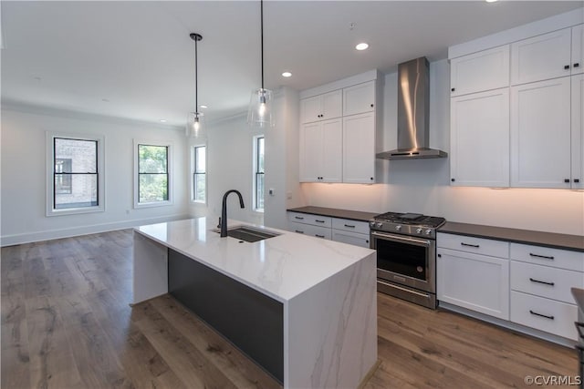 kitchen with wood finished floors, recessed lighting, a sink, gas range, and wall chimney range hood