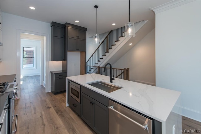 kitchen featuring light wood finished floors, recessed lighting, gray cabinets, stainless steel appliances, and a sink